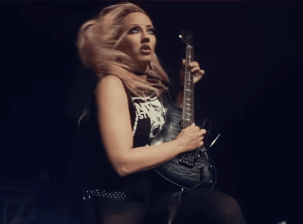 Nita Strauss rocks out in black attire on-stage.